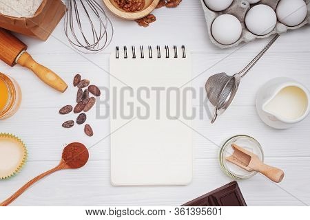 Ingredients And Utensils For Bakery Or Making Dessets And Blank Paper Notepad On The White Table.