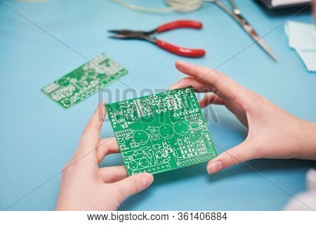 Microcontroller circuit board manufacture. Technician's hand with pcb