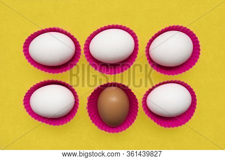 White Eggs And Brown Egg On The Yellow Background.