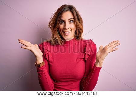 Young beautiful brunette woman wearing casual sweater stnding over pink background celebrating crazy and amazed for success with arms raised and open eyes screaming excited. Winner concept