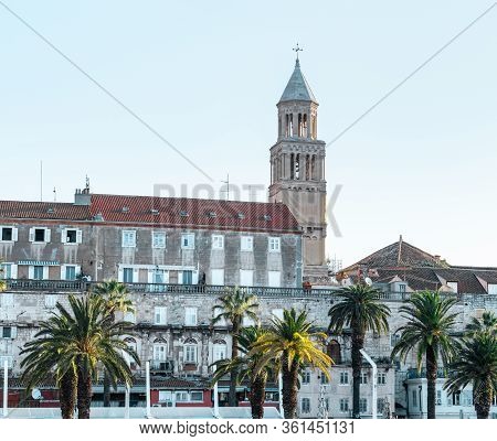 Riviera Of The Town Of Split, Croatia. Green Beautiful Palm Trees On The Shore. Old Belltower Of Sai