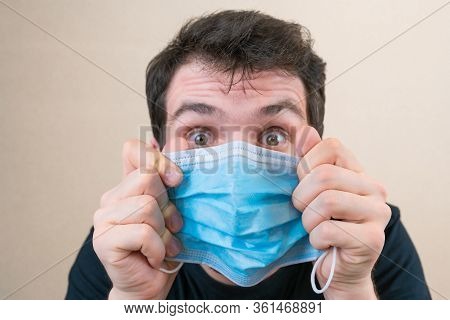 Young Man In Blue Protective Medical Mask And Happu With It. Self-isolation And Quarantine. Stay Hom