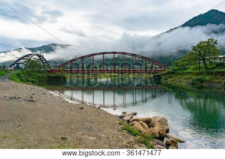 Red Bridge And River In The Mountain Valley. Japanese Countryside Landscape. Atera Valley In Kiso Va