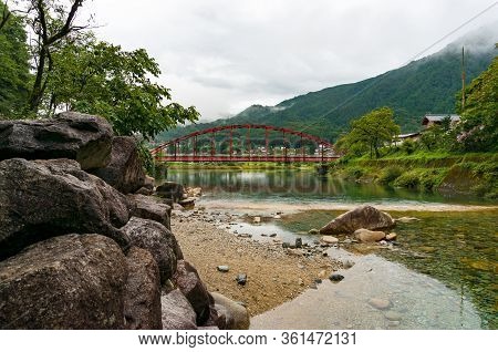 Red Bridge And River In The Mountain Valley. Japanese Countryside Landscape. Atera Valley In Kiso Va