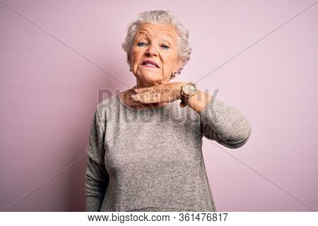 Senior beautiful woman wearing casual t-shirt standing over isolated pink background cutting throat with hand as knife, threaten aggression with furious violence