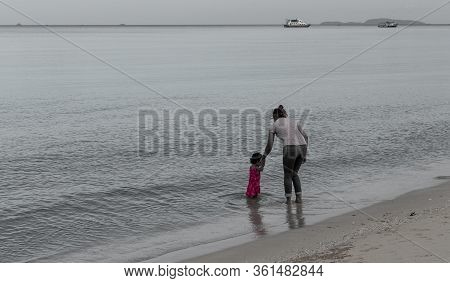Mother And Daughter Standing In Shallow Water With Island In The Background Holding Hands On Beach I