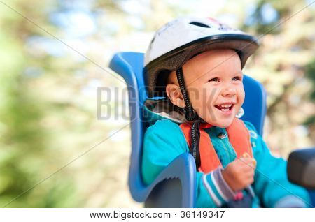 เด็กชายในจักรยานเด็กที่นั่งหัวเราะมีความสุข