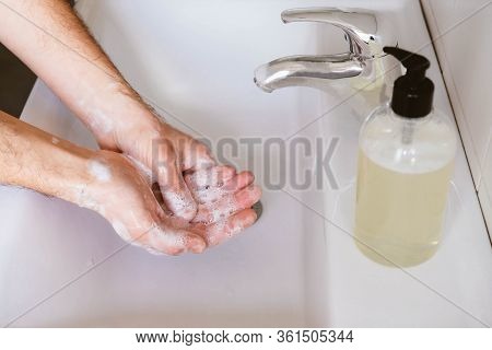 Man Cleaning His Hands Using Liquid Disinfectant Soap And Water In Bathroom.