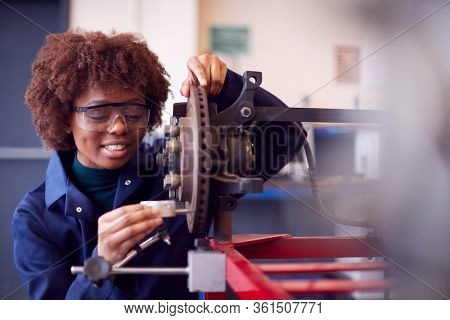 Female Student Working On Car Brakes On Auto Mechanic Apprenticeship Course At College