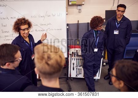 Female Tutor By Whiteboard With Students Teaching Auto Mechanic Apprenticeship At College