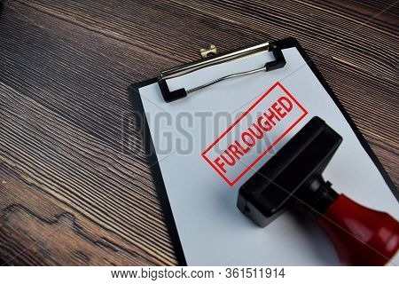 Red Handle Rubber Stamper And Furloughed Text Isolated On The Table.