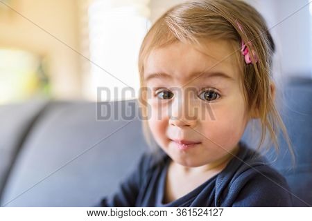 Two Year Old Girl With Big Eyas Portrait Looking Towards Camera Natural Light. Selective Focus