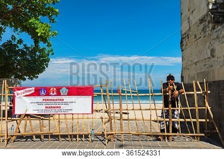 Kuta, Bali Island, Indonesia - April 16, 2020: Balinese Pecalang Man Stay By Warning Banner With Sig