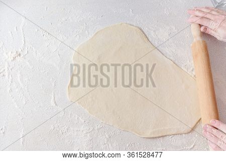 Сook Rolls Out The Dough With Rolling Pin On White Background. Cooking In The Kitchen Baking. Female