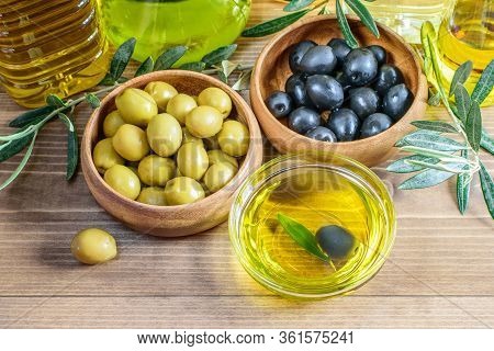 Black And Green Olives In Wooden Bowls, Olive Oil In Glss Transparent Bowl And Assortment Of Olive O