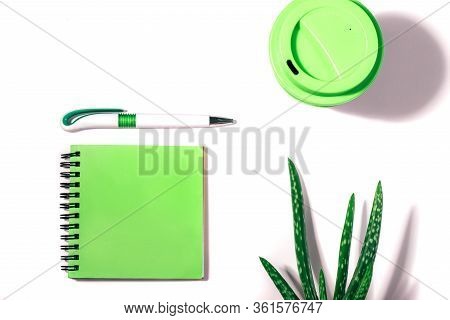 Flat Lay Of With Cropped Green Notepad, Pen, Reusable Coffee Cup And Aloe Vera Plant On White Backgr