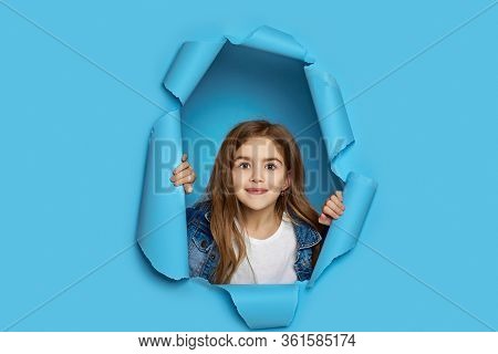 Portrait Of Cute Happy Smiling Caucasian Little Cild Girl Poses In Blue Paper Hole.