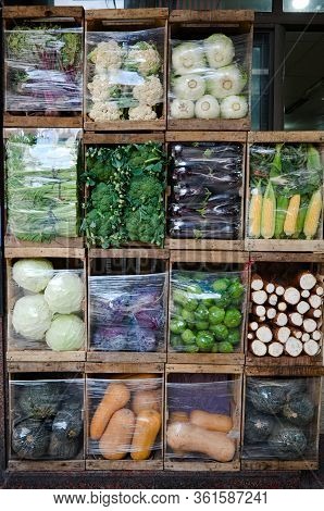 Street Market Vendor With Vegetables Packed In Wooden Boxes Like Cells To Demonstrate Variety Of Veg
