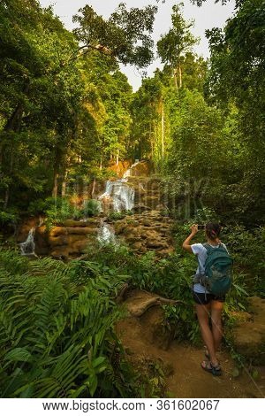 Woman Backpacker Taking Photo Of The Pha Charoen Waterfall Phop Phra District, Tak, Thailand