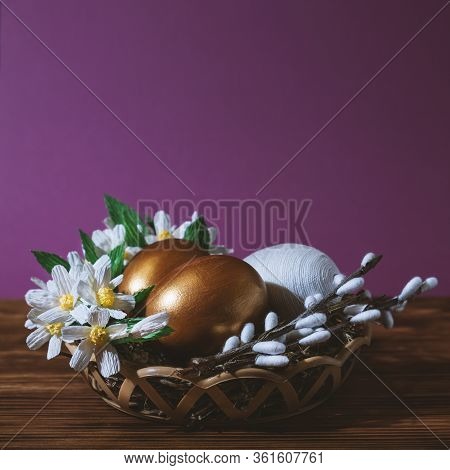 Easter Eggs In Basket Filled With Straw And Yellow Flowers And Willow. Preparation For Holiday. East