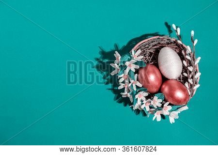 Easter Eggs In Basket Filled With Straw And Yellow Flowers And Willow. Preparation For Holiday. East