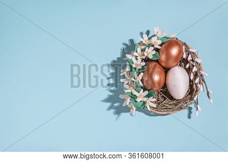 Easter Eggs In Basket Filled With Straw And Yellow Flowers And Willow. Preparation For Holiday. East