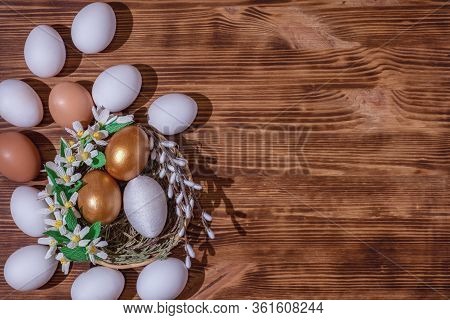Easter Eggs In Basket Filled With Straw And Yellow Flowers And Willow On Wooden Rustic Vintage Backg