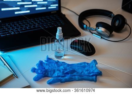 Sanitizer anti virus spray with protecive gloves on the working table with laptop, mouse, headphones. Personal hygiene concept. Concept of quarantine for coronavirus and working from home.