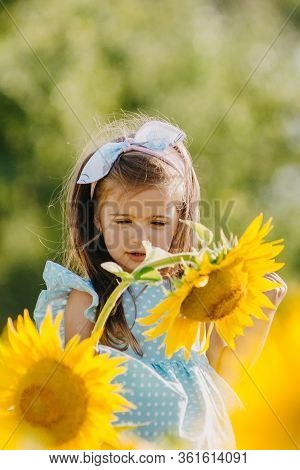 Little Cheerful Girl In A Field Of Yellow Sunflowers. Child And Sunflower, Summer, Nature And Fun. S