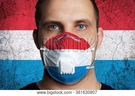 Young Man With Sore Eyes In A Medical Mask Painted In The Colors Of The National Flag Of Luxembourg.