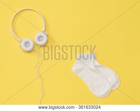 White Headphones With A Wire And White Socks On A Yellow Background. The Color Trend. The Concept Of