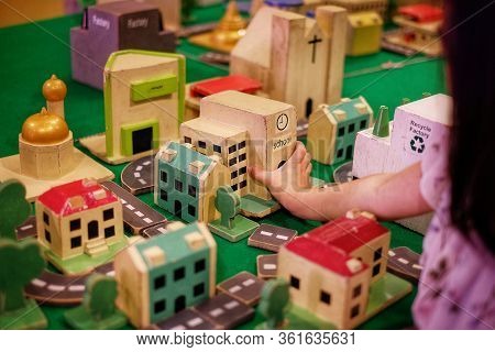 A Girl Adding A School Wooden Block To Her Modeled Town