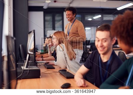Group Of College Students With Tutor Studying Computer Design Sitting At Monitors In Classroom