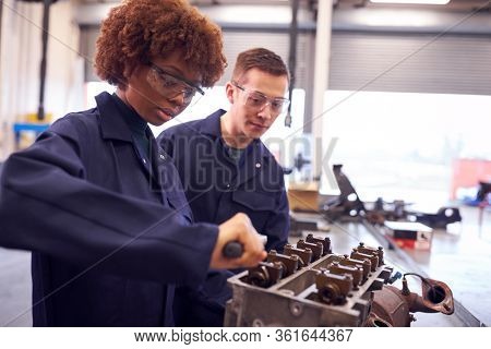 Male And Female Students Work On Car Engine Block On Auto Mechanic Apprenticeship Course At College