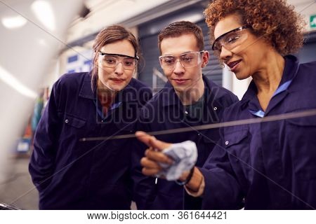 Female Tutor With Students Checking Oil Level In Car Engine On Auto Mechanic Course At College