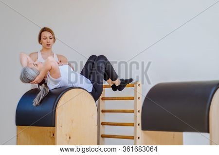 Pilates Reformer Eldery Blond Curly Woman Gym Fitness Teacher Workout Back And Hands Exercise On Pil