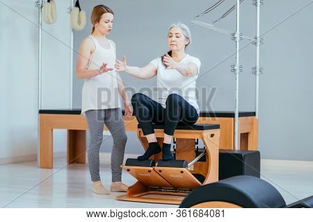 Older Women Doing Pushups. Young Personal Trainer Helping Senior Woman. Workout In Rehabilitation Ce