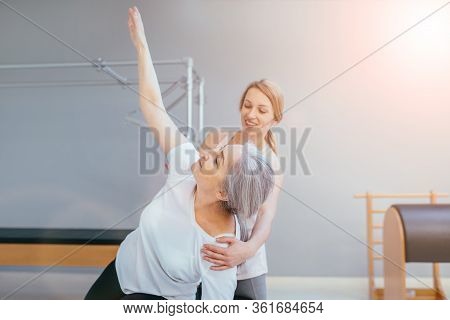 Pilates Lesson On Reformer, Personal Coach In Black Sportswear Workout With Sporty Eldery Beautiful 