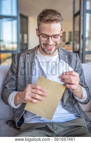 Young Man In Eyglasses Opening The Envelope