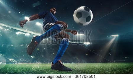 Professional Football Or Soccer Player In Action On Stadium With Flashlights, Kicking Ball For Winni