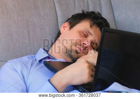 Portrait Of Tired Man Sleeping Working Overtime On Laptop Sitting On Couch At Home With Computer In 
