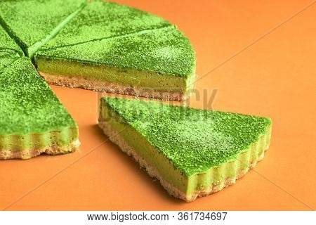 Green Cheesecake Made With Matcha Tea Powder On An Orange Background. Single Slice Of Green Jiggly C