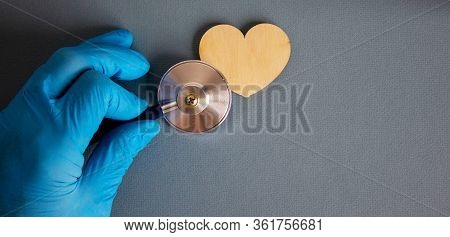 Wooden Heart, Hand In Blue Glove And Stethoscope.