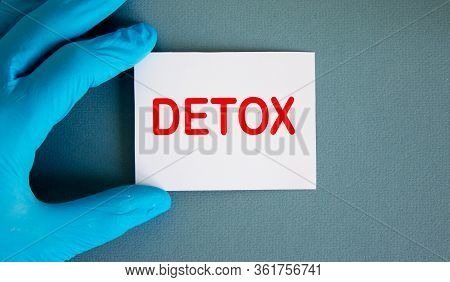 Hand In Blue Glove With White Card. Concept Word Detox.