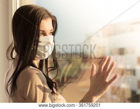 Young woman with veil looking at window, home isolation concept. Covid-19 pandemic situation in self isolation at home. New corona virus changes normal lives.