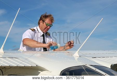 Flight Instructor In Uniform Doing Pre-flight Check Returning Fuel Back To Tank After Checking It Be