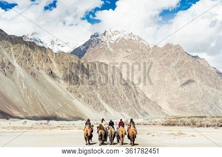 A Group Of People Enjoy Riding A Camel Walking On A Sand Dune In Hunder, Hunder Is A Village In The 