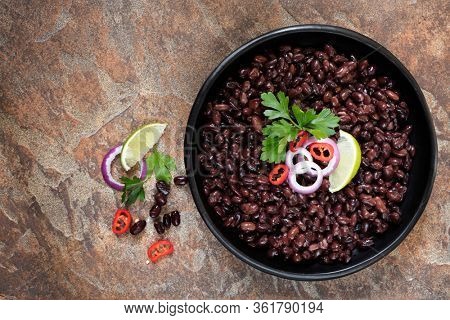 Black beans in rustic bowl over slate background