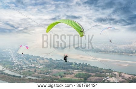 Paragliding In The Sky. Paraglider  Flying Over Landscape From Beautiful View Mekong River At Wat Ph