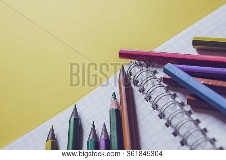 School Supplies On Yellow. Bright Back To School Background. Notepad And Stack Of Colorful Pencils. 